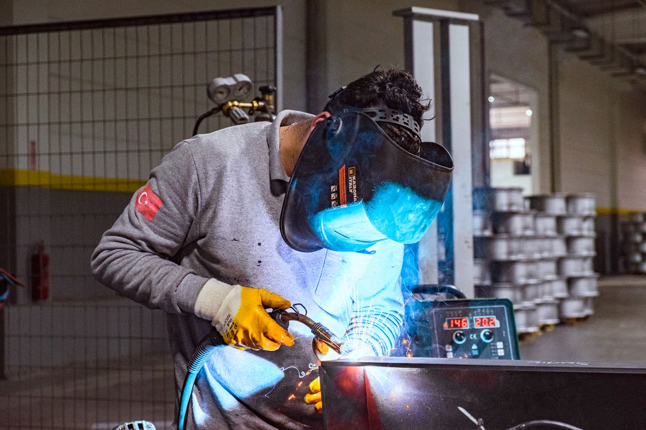 Mesleki eğitim atölyesinde öğrenciler ile yerel işletme uzmanının teknik ekipman üzerinde çalışması